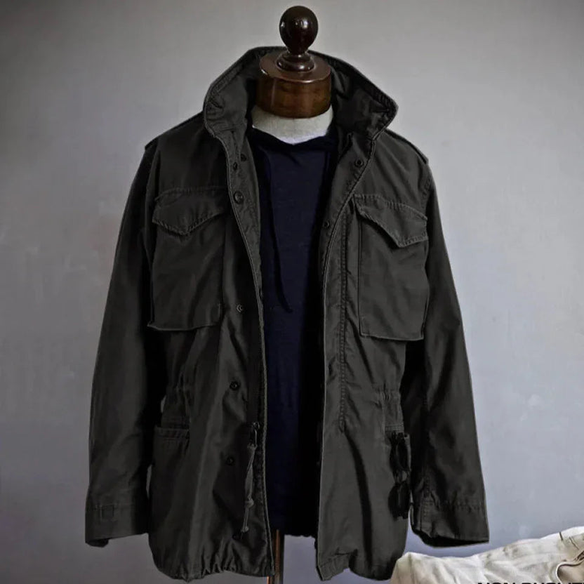 Men's durable utility field jacket designed for outdoor activities, featuring multiple pockets for storage and a rugged, weather-resistant fabric suitable for various environments. 1